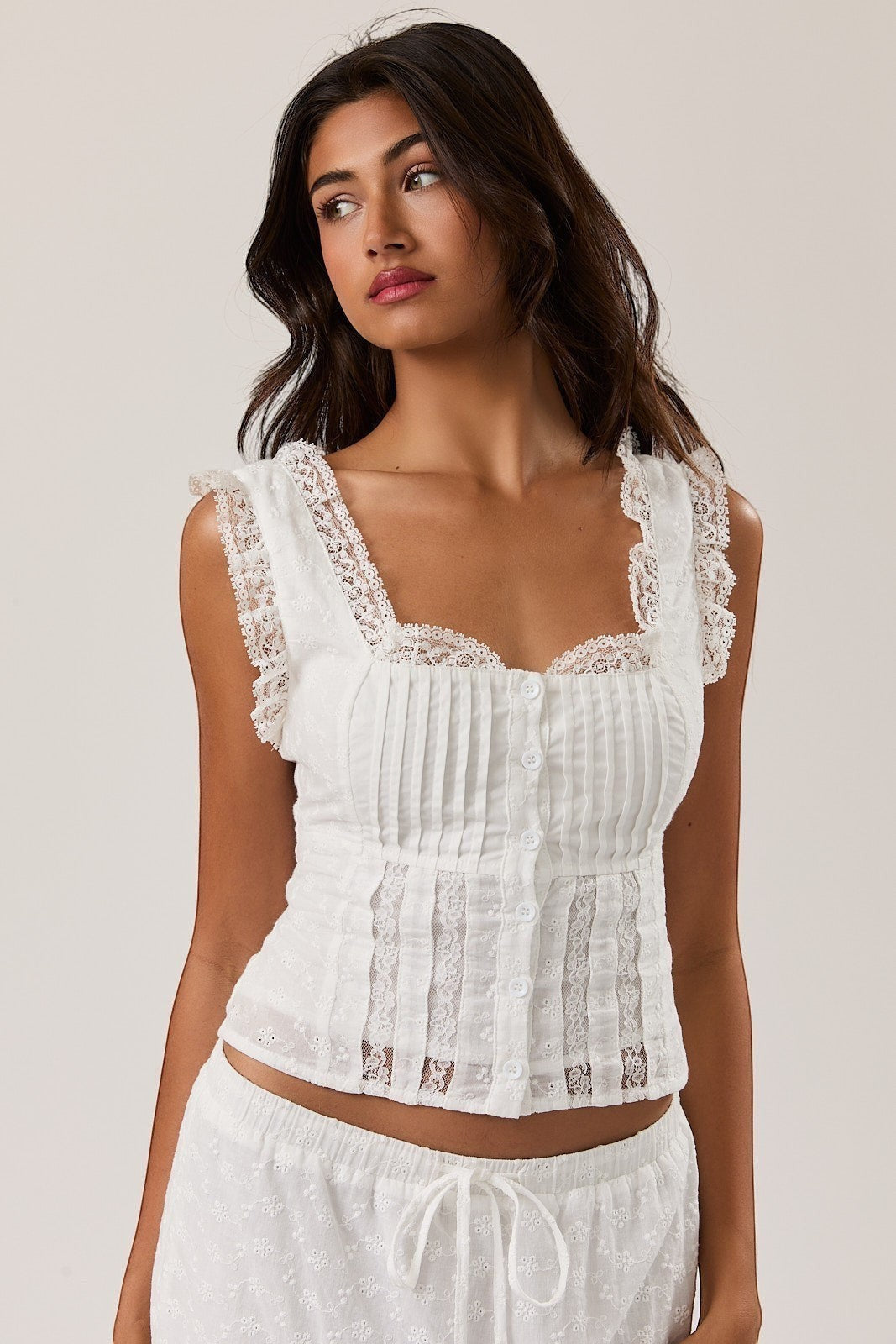 Mad-ly white lace corset blouse with a square neckline, pleated bodice, and ruffled cap sleeves on a model.